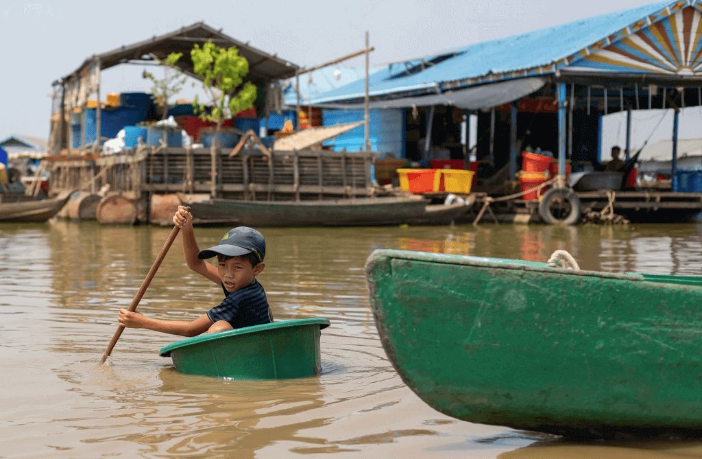 A boy paddling a plastic tub at Chong Kneas floating village — the photo used in the Urbanist Hanoi feature