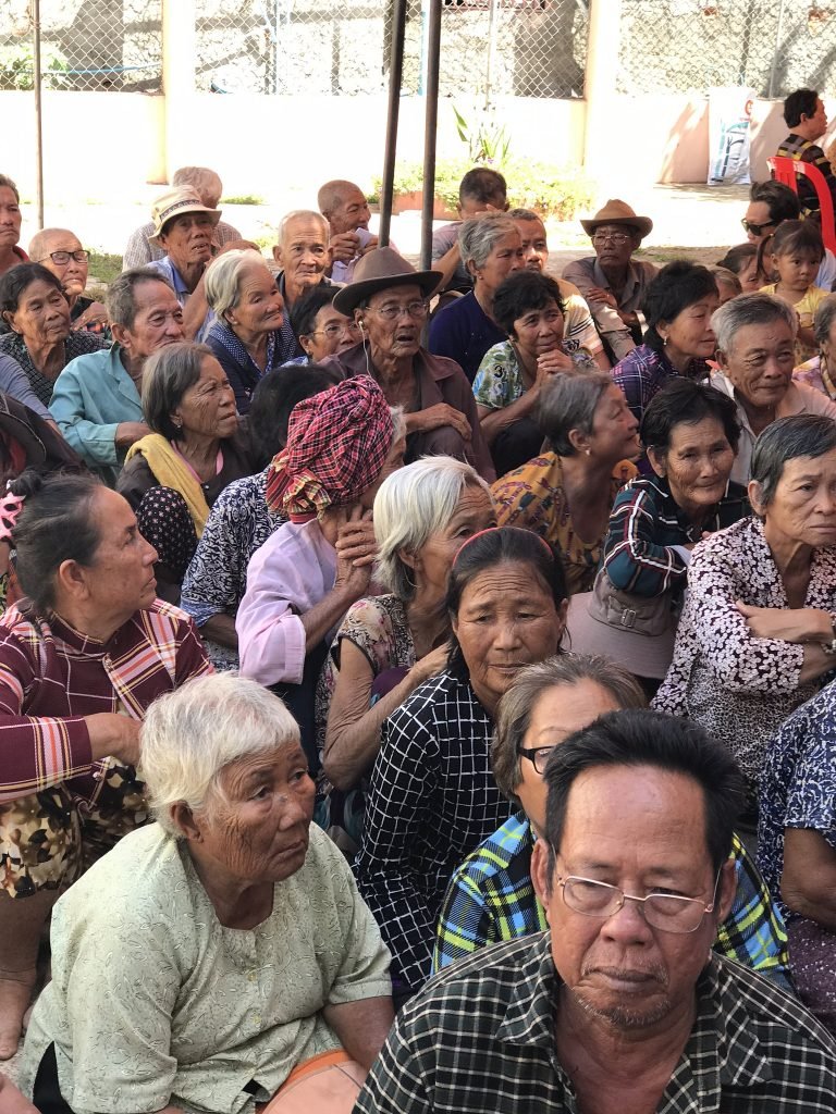 A large gathering of elderly ethnic Vietnamese men and women at a community meeting in Cambodia — the families displaced from the Tonle Sap floating villages