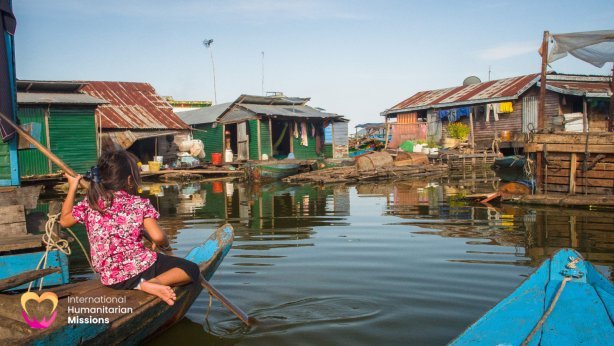A young girl paddling a boat through the narrow waterways of a floating village in Tonle Sap, Cambodia