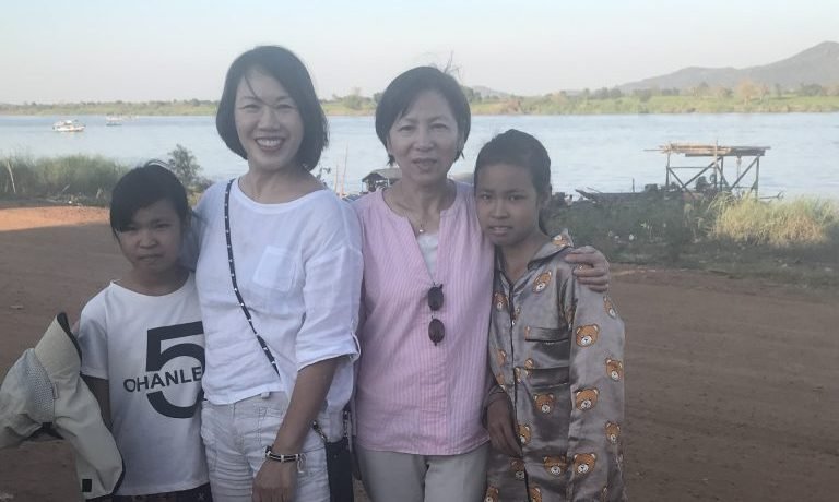 IHM volunteers with two young stateless Vietnamese sisters near the Tonle Sap River